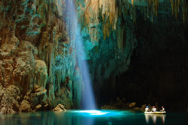 The interior of Anhumas Abyss lit up by a ray of sun entering through a natural skylight.